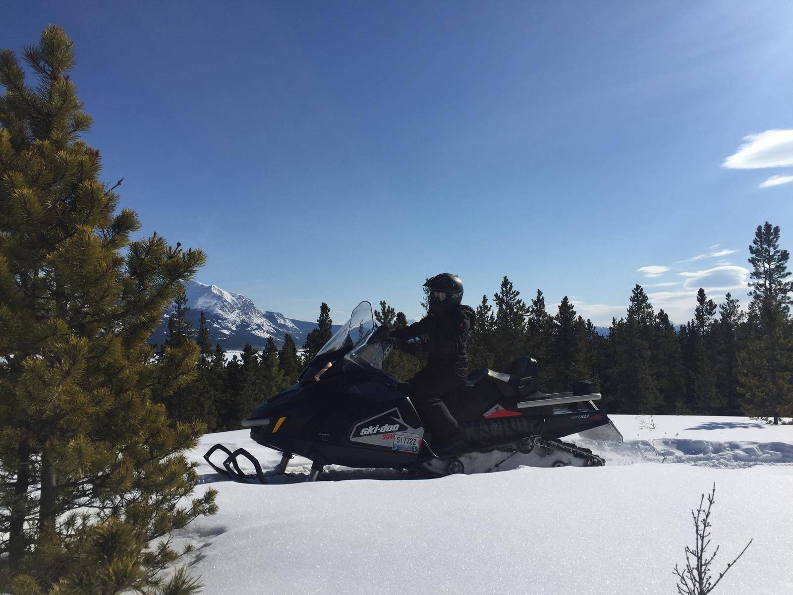 A person riding a skidoo in the forest in thick snow