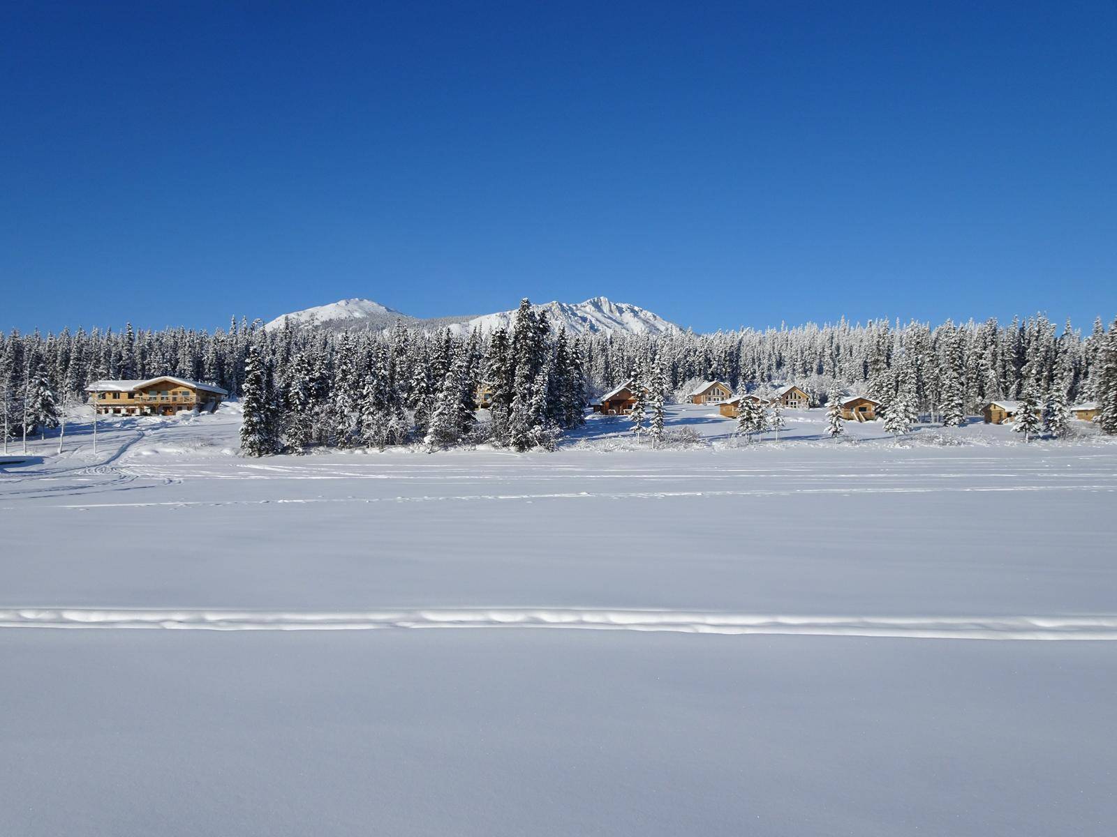 View from the frozen lake to the property and mountains in deep winter