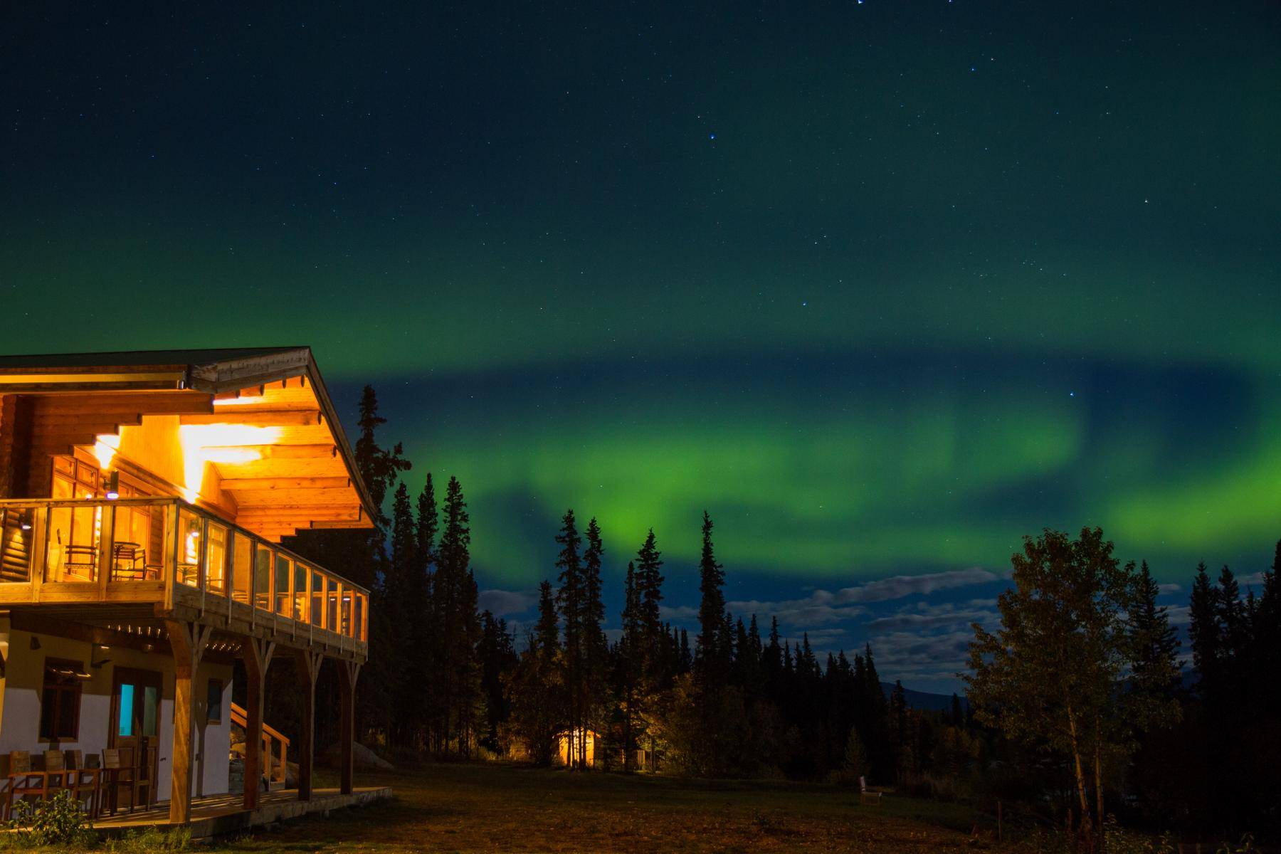lit main house in summer at night with northern lights in the sky