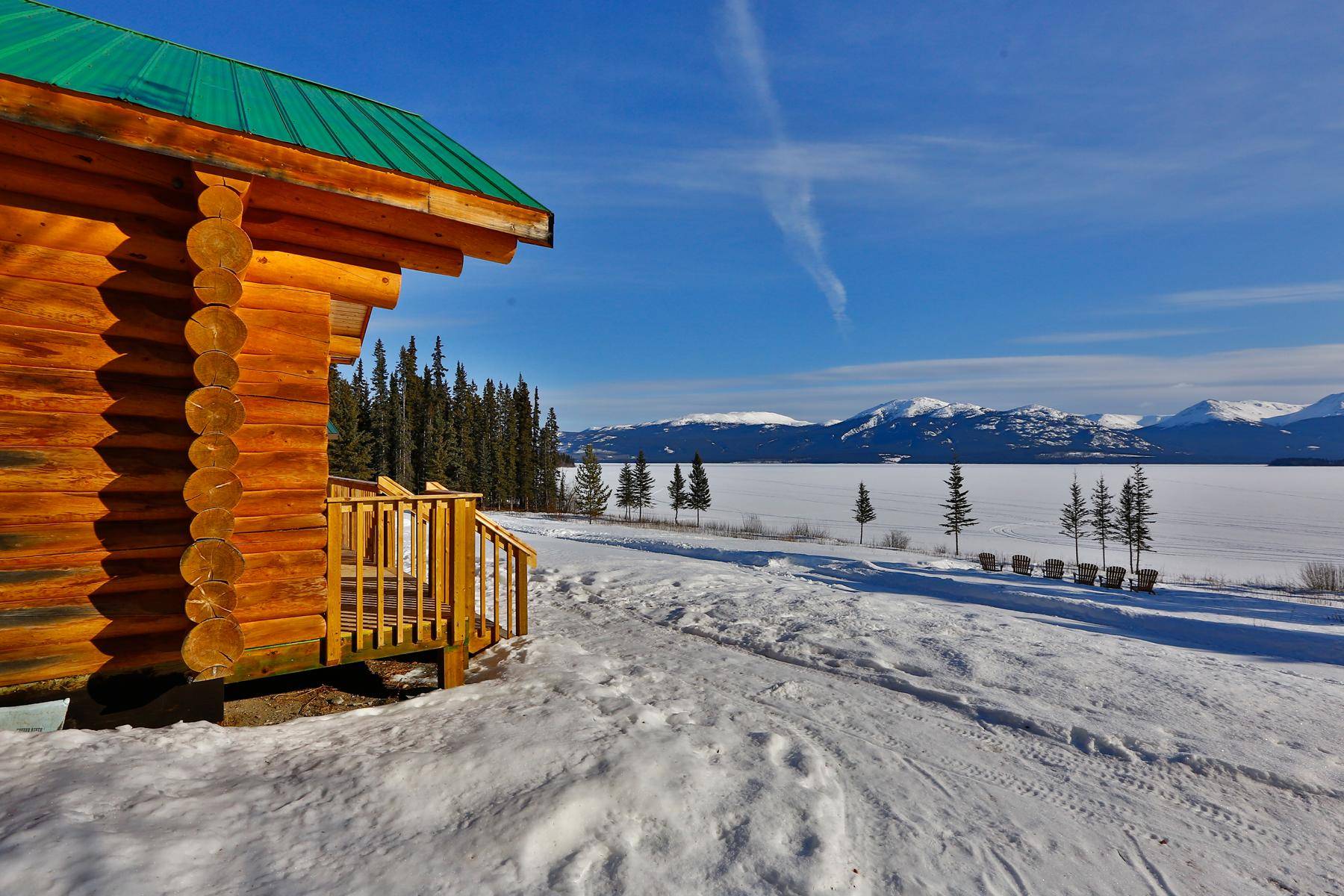View along a cabin on the frozen lake and mountains in deep winter