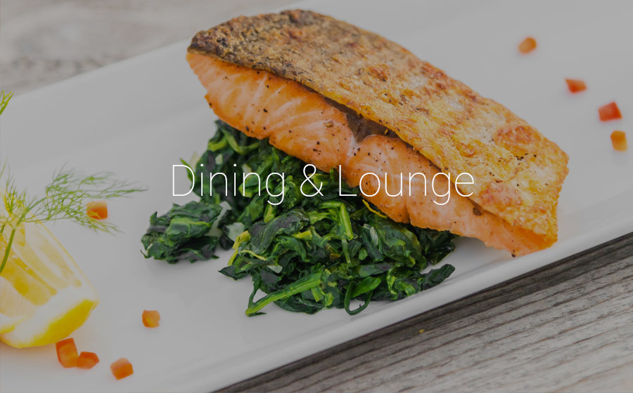 Plate with salmon and spinach with text overlay "dining & lounge". Links to dining page.